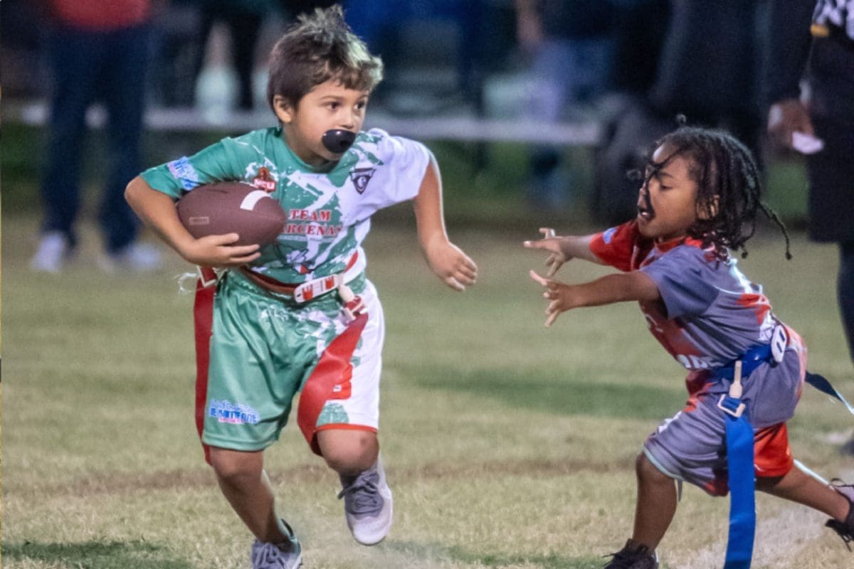 Two young children playing football on a field.