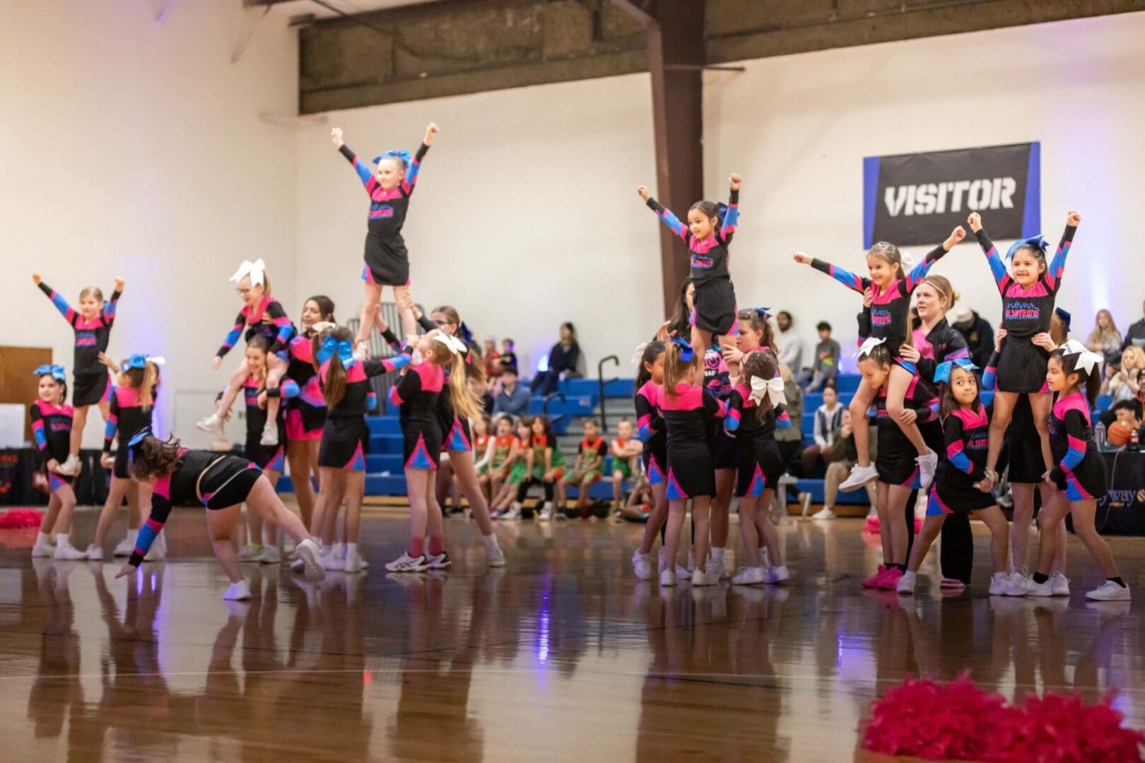 Cheerleaders performing routine in gymnasium.