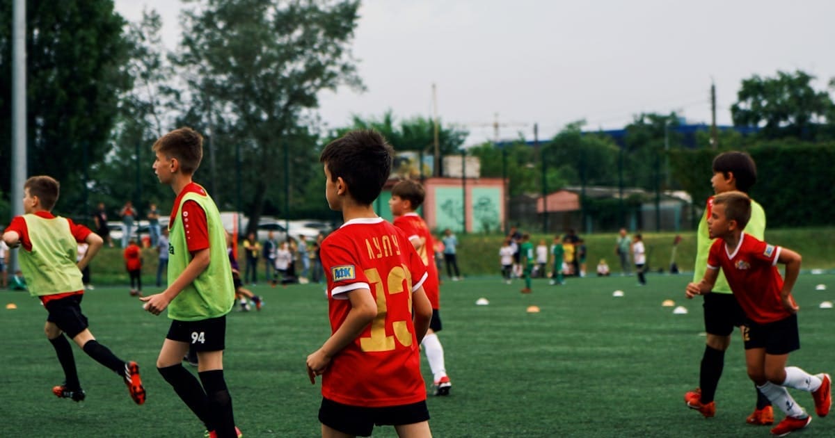 Children playing soccer on a green field.