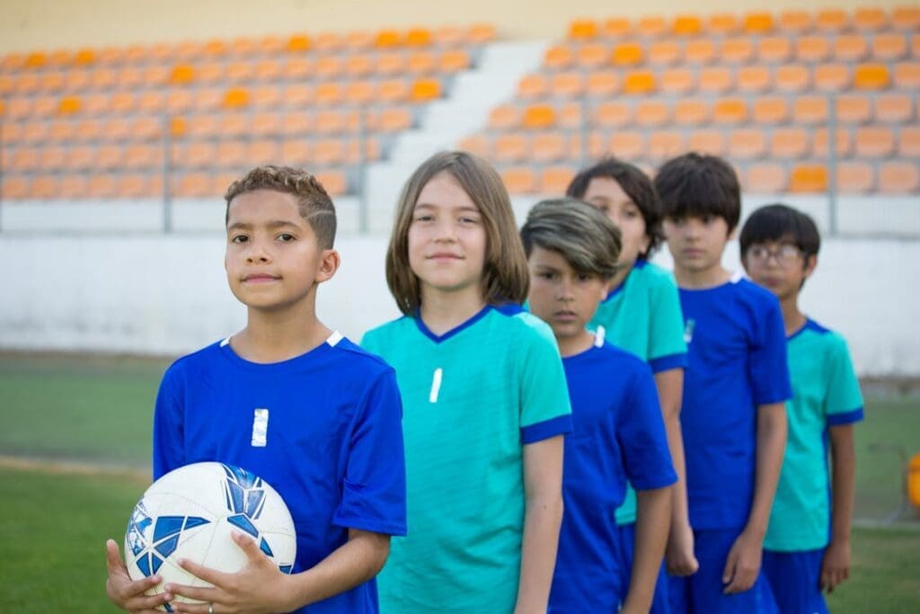 Group of young athletes in soccer uniforms standing confidently on a sports field