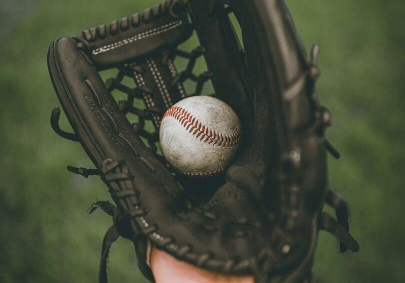 Baseball glove holding a baseball outdoors.