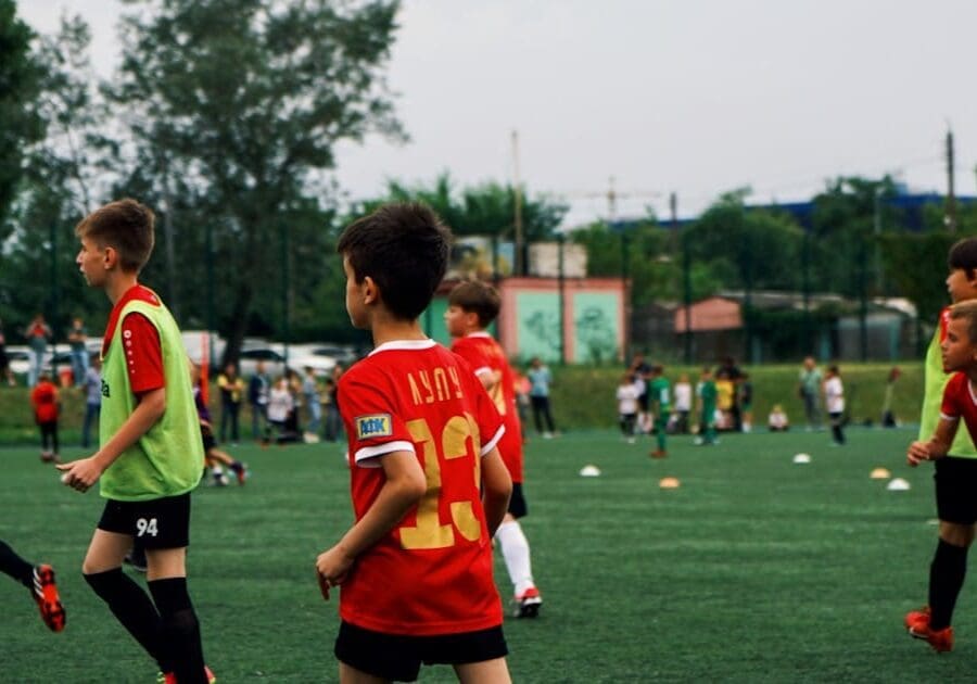 Children playing soccer on a green field.