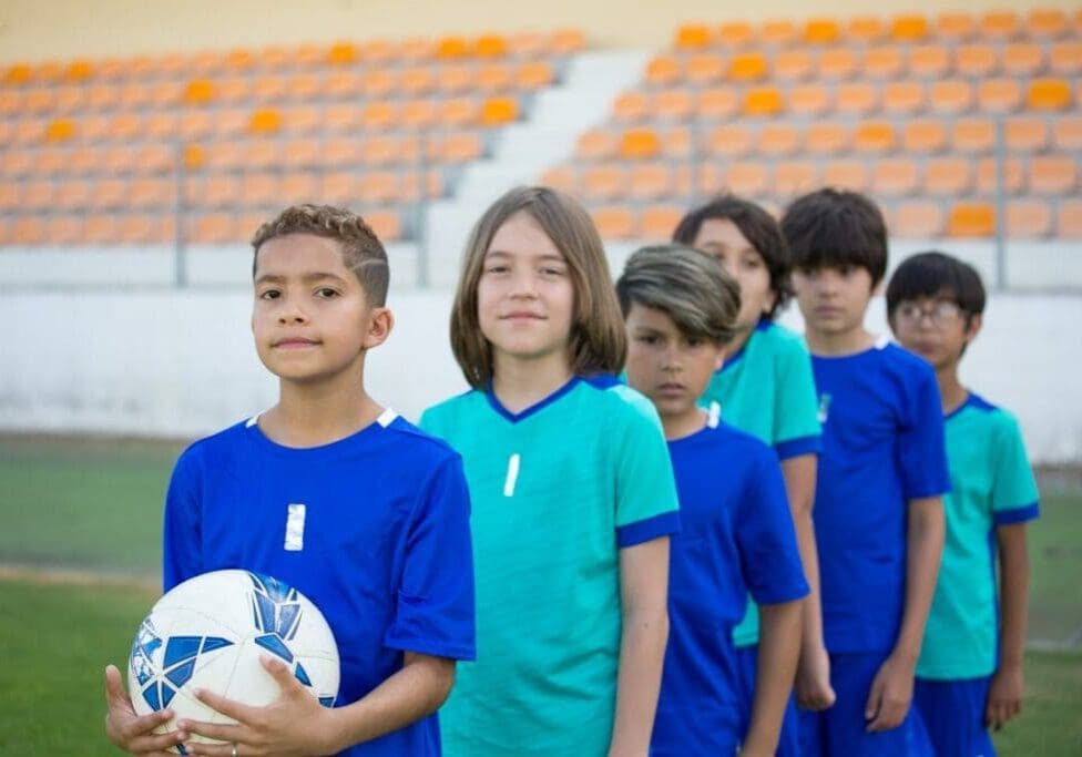 Group of young athletes in soccer uniforms standing confidently on a sports field